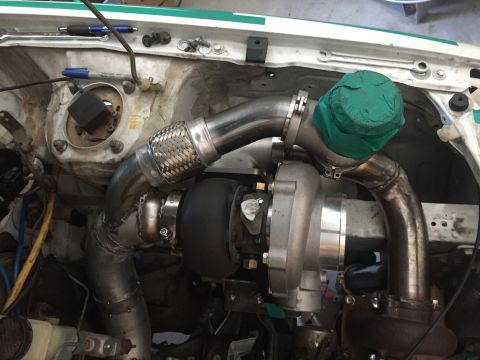 1993 Mercury Tracer - Custom turbocharger installation in an engine bay, stainless steel piping and a green protective cover.