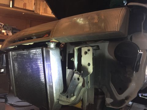 1993 Mercury Tracer - Front end of a car undergoing repair, revealing the radiator, headlight, and internal support structures.