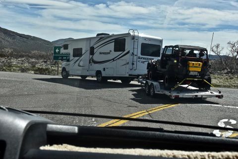 1992 Jeep Wrangler - A black Jeep Wrangler is transported on a trailer behind a Sunseeker RV on a highway.