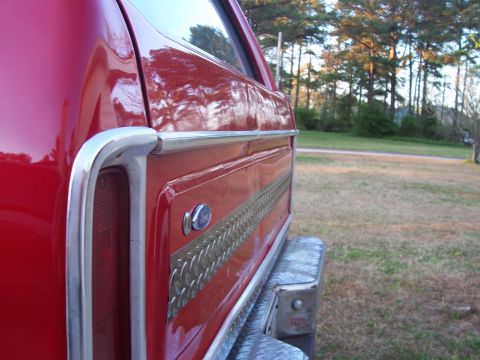 1979 Ford Bronco - Rear quarter panel detail of a red 1979 Ford Bronco, showing chrome trim and a decorative side strip.