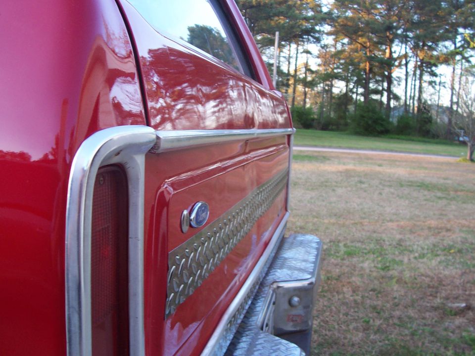 Red 1979 Ford Bronco rear quarter panel with chrome trim and decorative strip