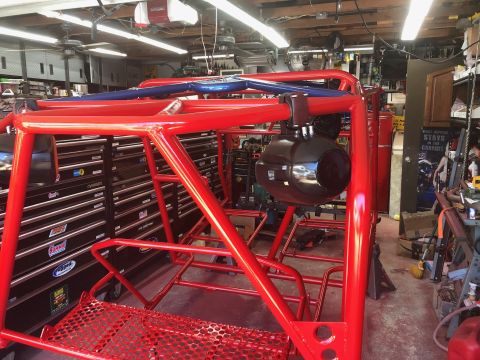1992 Jeep Wrangler - A red roll cage structure is assembled in a garage setting, with tool chests visible.