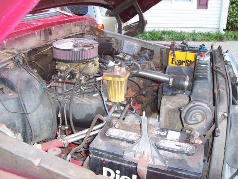 1979 Ford Bronco - The engine bay of a 1979 Ford Bronco shows a V8 engine with an aftermarket air cleaner and dual batteries.