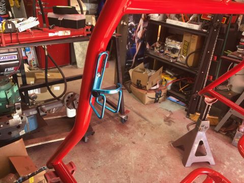 1992 Jeep Wrangler - A red roll cage section is visible with a blue bottle holder, set against a workshop background.