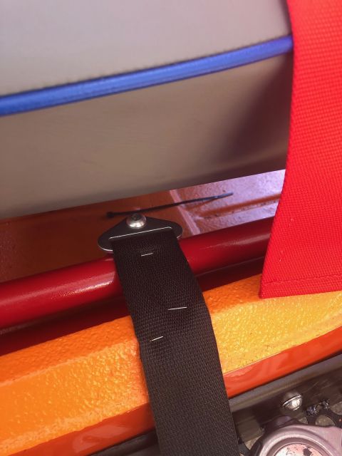 1992 Jeep Wrangler - Close-up of a seatbelt mounting bracket and strap against an orange and red interior.