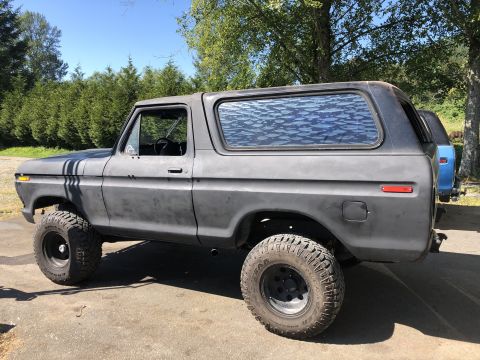 1978 Ford Bronco - Side view of a matte gray 1978 Ford Bronco with lifted suspension and off-road tires.