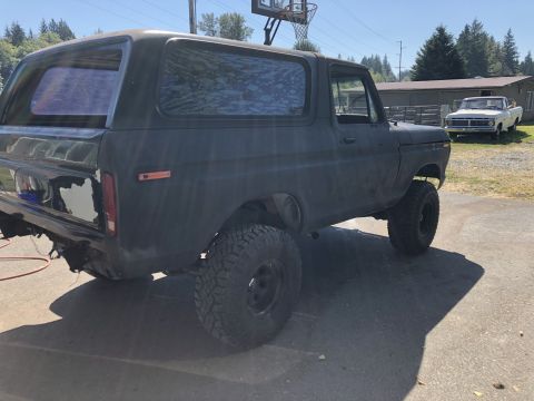 1978 Ford Bronco - This 1978 Ford Bronco is shown from a three-quarter front view, with a white pickup truck in the background.
