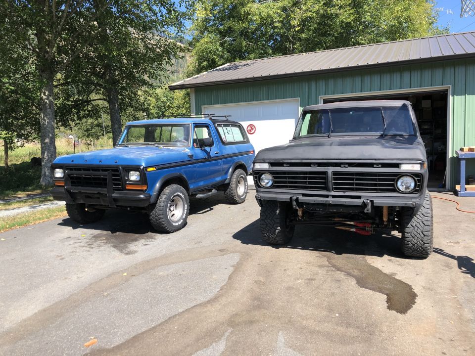 Blue 1978 Ford Bronco parked next to a matte black one
