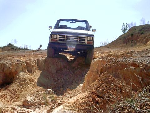 1985 Ford Bronco - Ford Bronco navigates a challenging off-road course on a sunny day.
