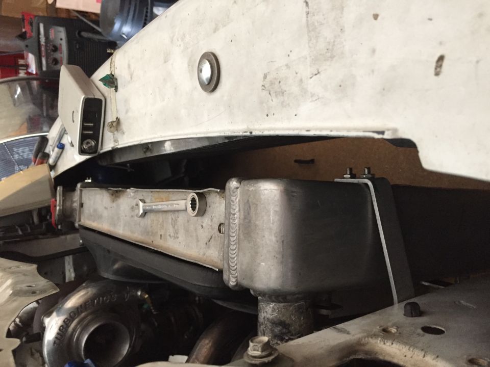 Engine bay showing a turbocharger and custom radiator setup. A wrench rests on the radiator