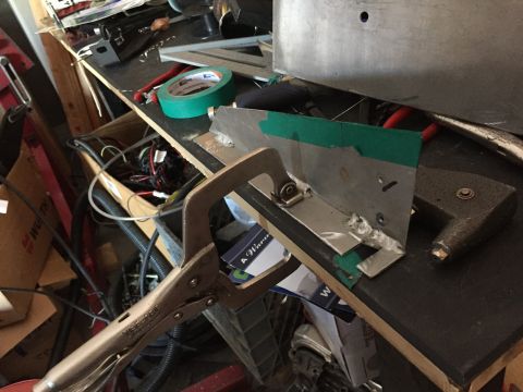 1993 Mercury Tracer - A workbench is cluttered with tools, tape, and metal parts being held by a clamp.
