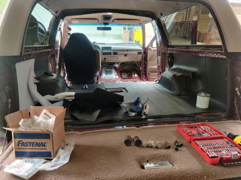 1996 Ford Bronco - Interior of a 1996 Ford Bronco undergoing sound deadening and flooring work, with tools and parts visible.