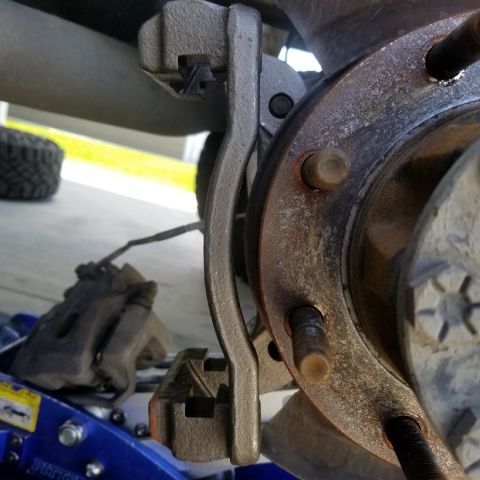 2001 Ford Excursion - Close-up view of a vehicle's brake caliper and rotor assembly, with a blue jack visible below.