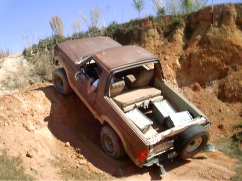 1985 Ford Bronco - Ford Bronco navigating a steep dirt incline, carrying cargo in its bed.