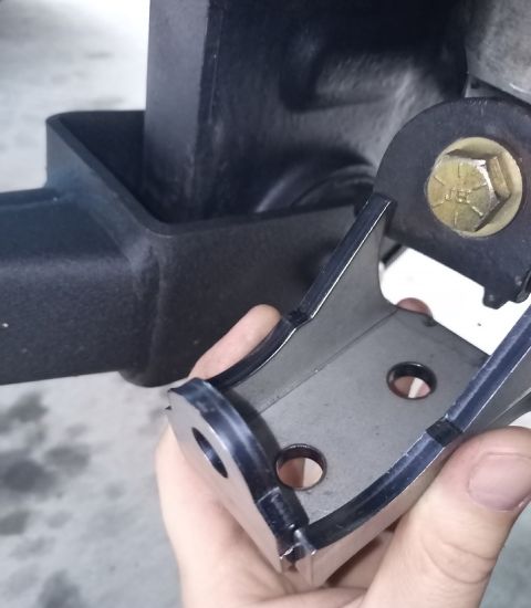 2001 Ford Excursion - A metal bracket is shown being held and attached to a black hitch receiver, with a Supermotors.net watermark visible.
