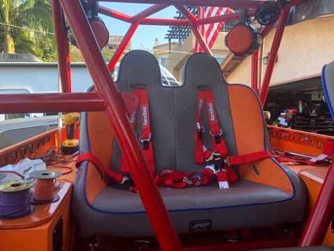 1992 Jeep Wrangler - Custom off-road vehicle interior features PRP racing seats with red harnesses and a prominent red roll cage structure.