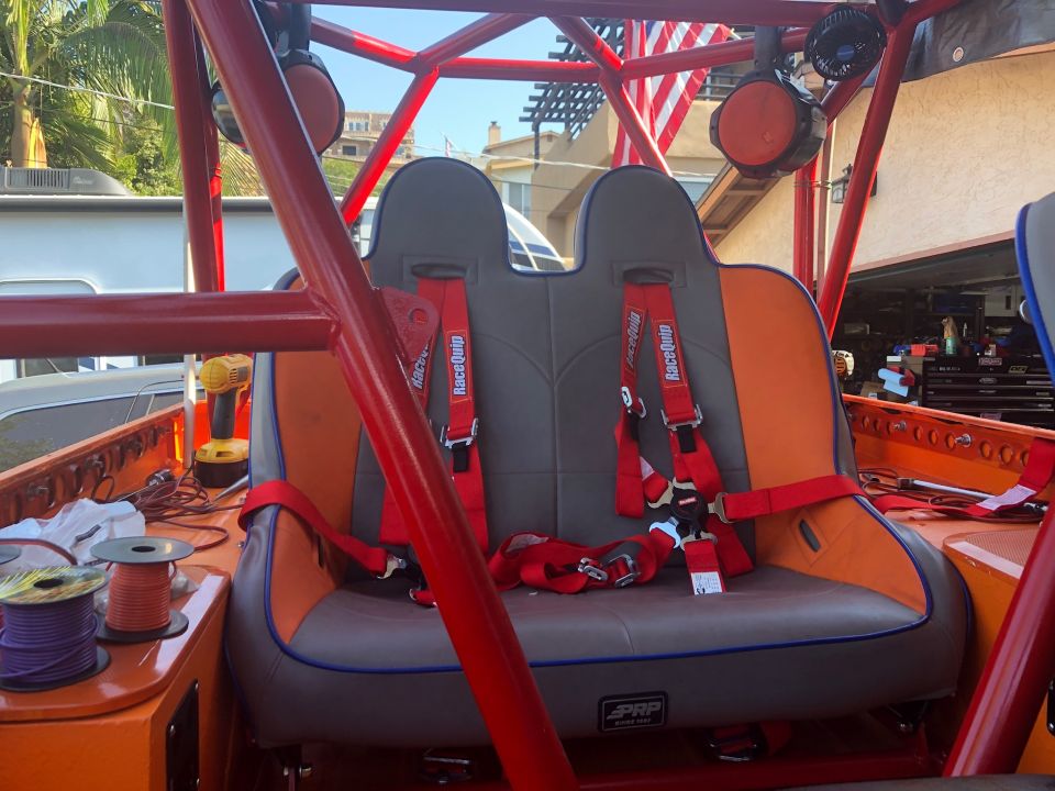 Interior of custom off-road vehicle with PRP racing seats, red harnesses, and roll cage