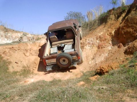 1985 Ford Bronco - This SUV appears to be struggling on a steep dirt hill, with its rear end angled upwards.