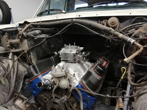 1996 Ford Bronco - Close-up view of a V8 engine in an engine bay, a carburetor and "RACING" branded valve covers.
