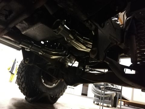 1996 Ford Bronco - A view of the undercarriage and exhaust system of a vehicle, with a large tire visible.