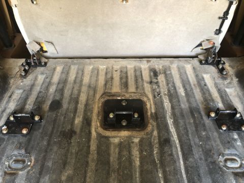 1980 Ford Bronco - The rear cargo area of a vehicle, showing the floor and the underside of a folded seat with mounting brackets.