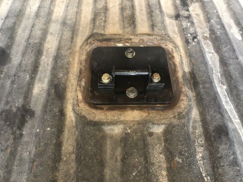 1980 Ford Bronco - Close-up of a mounting bracket installed on a vehicle's bed floor.