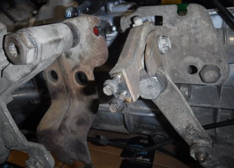 1992 Ford Bronco - Side-by-side view of the E4OD t-case shifter linkage plate (left) and M5OD plate (bolted on at right). The portion with the right bolt on t…