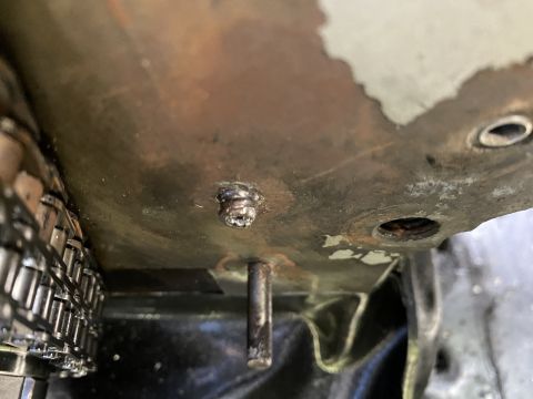 Close-up of a timing chain and a metal plate with a screw and a pin