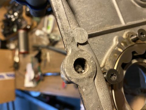 Close-up of a metal engine component with a bolt and gear teeth visible