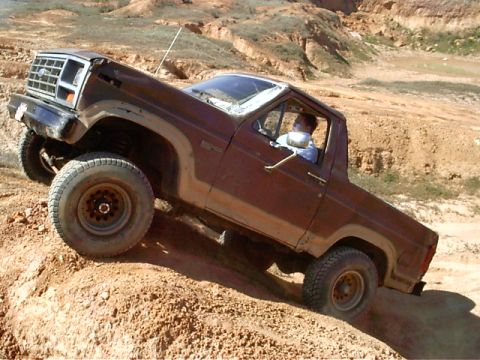 1985 Ford Bronco - 1985 Ford Bronco navigating challenging off-road terrain.