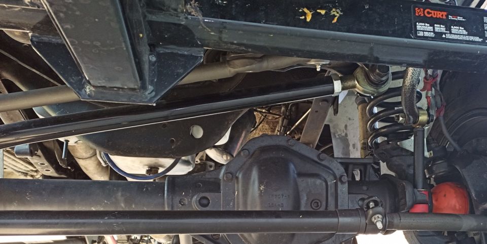 Underside view of a truck's suspension and differential. Shows a CURT hitch label