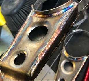 1979 Ford Bronco - A close-up view of a custom-welded exhaust component, showing the intricate metalwork and heat treatment. The Supermotors.net logo is visib…
