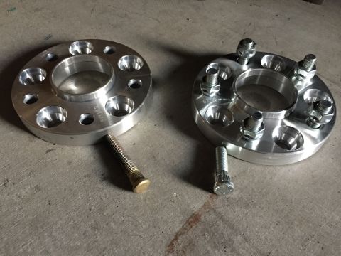 1993 Mercury Tracer - Two aluminum wheel spacers are shown on a concrete surface, with bolts nearby.