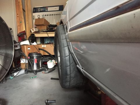 1993 Mercury Tracer - A close-up side view of a car's fender and tire in a cluttered garage setting.