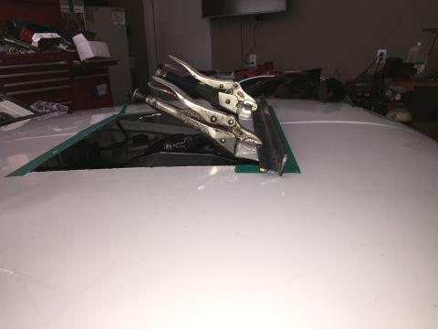 1993 Mercury Tracer - Vice grips are used to hold a cut-out sunroof in place on a white car's roof.