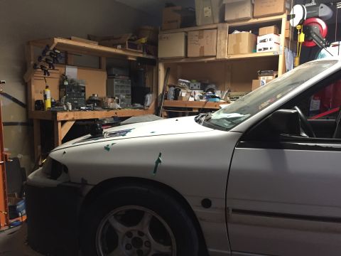 1993 Mercury Tracer - The 1993 Mercury Tracer is seen in a garage, partially obscured by a workbench and storage shelves.