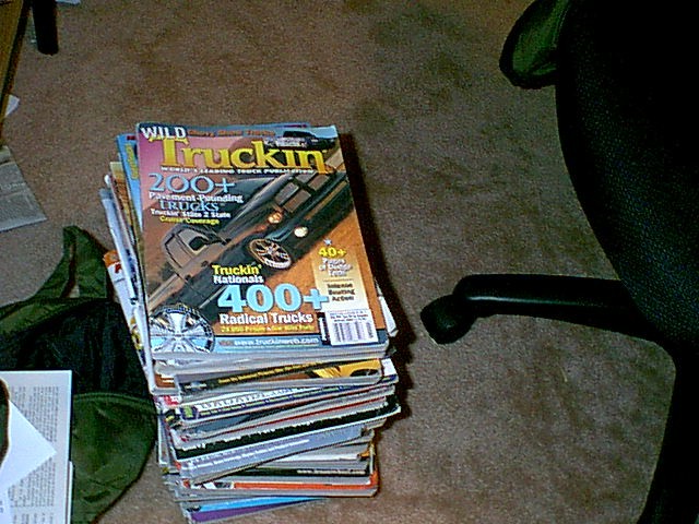 Stack of 'Wild Truckin' magazines on carpet next to a chair