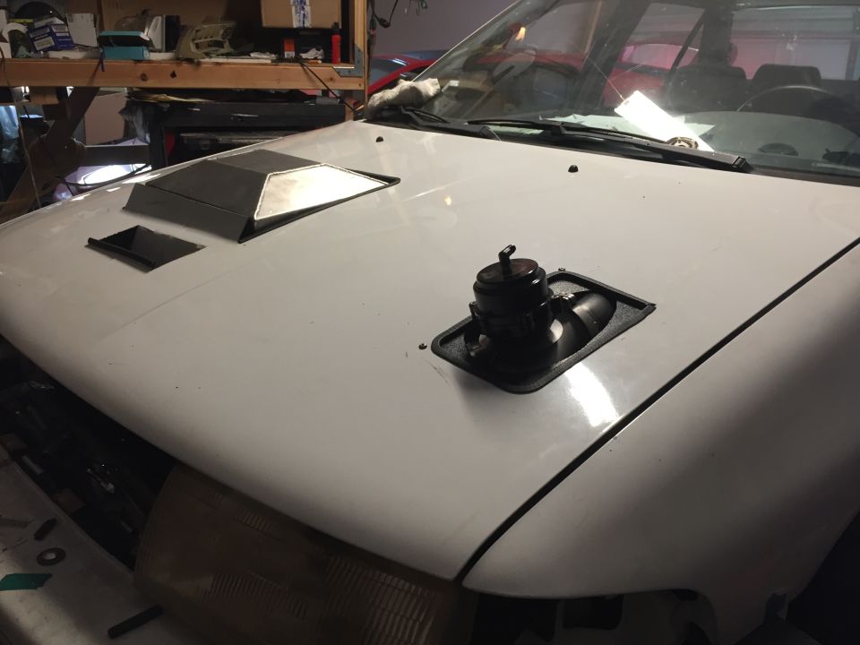 White car hood with a large metal vent and a black blow-off valve installed