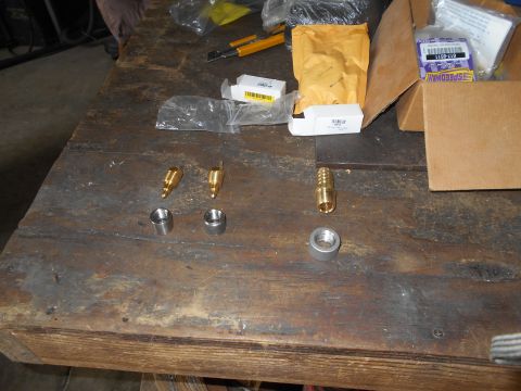 1992 Ford Bronco - Various metal fittings and packaging are laid out on a wooden workbench.