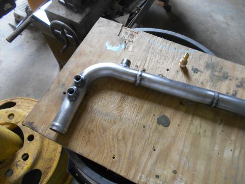 1992 Ford Bronco - A custom-fabricated metal pipe with various fittings is shown resting on a wooden workbench.