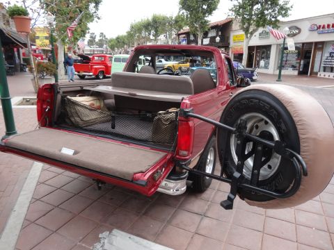 1994 Ford Bronco - Red convertible SUV with tailgate open and spare tire mounted externally.