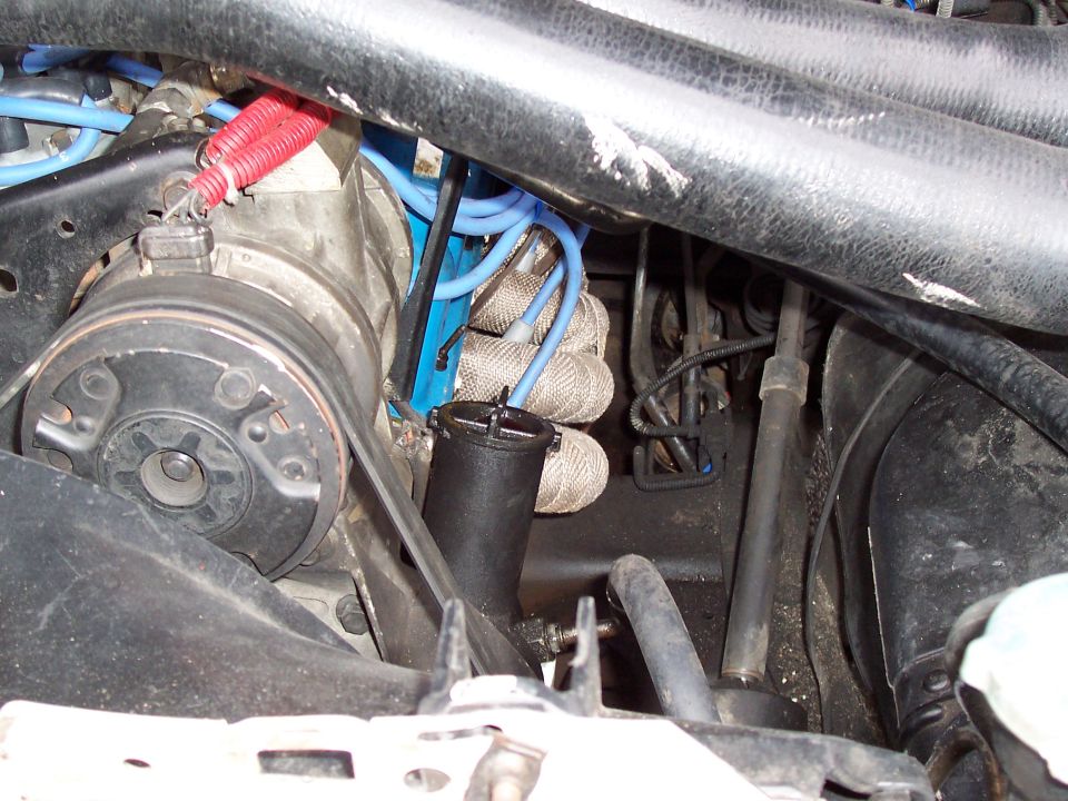 Engine bay close-up with blue spark plug wires, heat-shielded boots, pulley and belt on a 1987 Ford Bronco