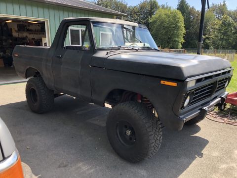 1978 Ford Bronco - Matte black 1978 Ford Bronco parked in front of a garage with lifted suspension.
