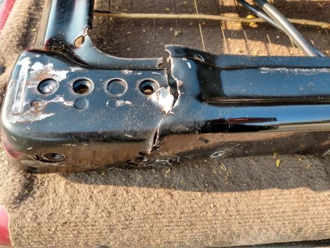 1994 Ford Bronco - The seat frame shows significant damage, including a large crack and missing paint, indicating it's a worn or broken part.