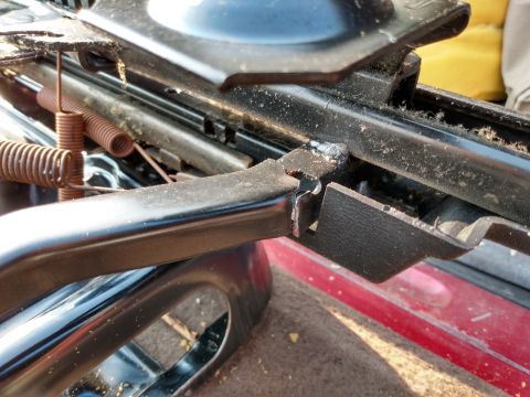 1994 Ford Bronco - A close-up view of a damaged vehicle seat mechanism, revealing internal components and signs of disrepair.