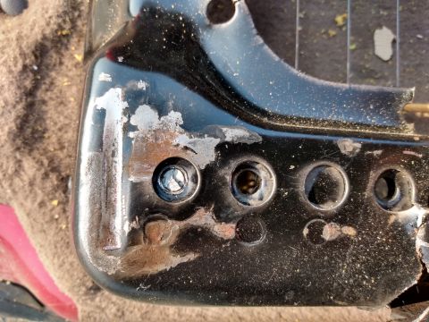 1994 Ford Bronco - A close-up view of a worn metal bracket, showing signs of rust and wear around the bolt holes.