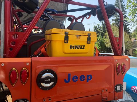 1992 Jeep Wrangler - Rear view of an orange Jeep with a yellow cooler and custom roll cage visible.