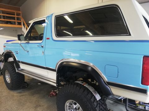 1996 Ford Bronco - This lifted SUV features a two-tone blue and white paint scheme and prominent off-road tires.