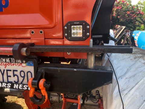 1992 Jeep Wrangler - Rear view of an orange Jeep showing aftermarket bumper, tow hitch, and auxiliary lights.