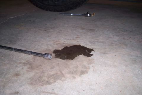 1978 Ford Bronco - Tools and an oil stain on a concrete floor suggest maintenance or a leak.